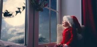 Vauva katsoo taivaalla lentävää joulupukkia ja poroja.