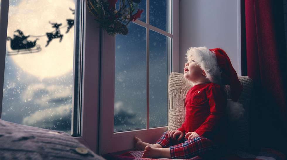 Vauva katsoo taivaalla lentävää joulupukkia ja poroja.