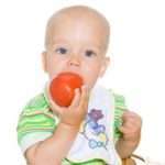 Child eating red tomato