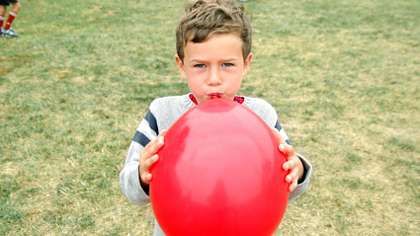 Poika puhaltaa ilmapalloa