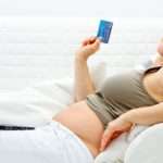 Happy beautiful pregnant woman using credit card to shop from  internet