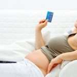 Happy beautiful pregnant woman using credit card to shop from  internet