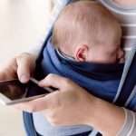unrecognizable-mother-with-her-son-in-sling-holding-smartphone-picture-id625758184