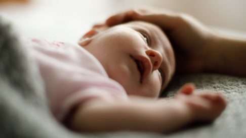 Silittele vauvaa sängyssään ja kokeile sitten, nukahtaisiko hän itsekseen. Vauvat, jotka osaavat rauhoittua unille itsekseen nukkuvat yleensä levollisemmin kuin nukuttamiseen tottuneet ikätoverinsa. Kuva: iStock