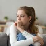 Sad woman sitting on couch alone at home