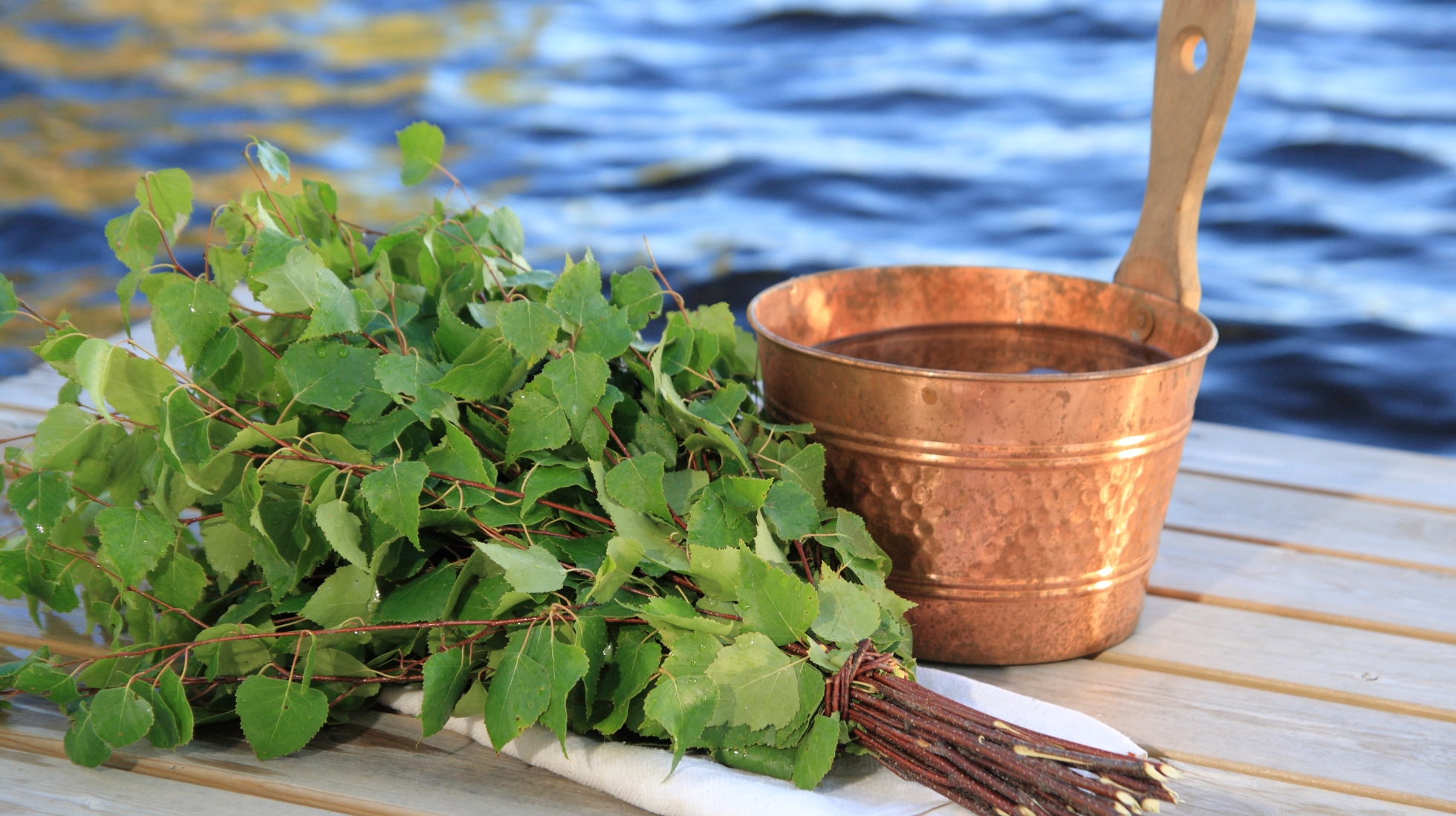 Löylykiulu ja vihta laiturilla. Taustalla meri.