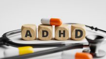 Puupalat, jotka muodostavat kirjaimet ADHD. Ympärillä lääkkeitä ja stetoskooppi.