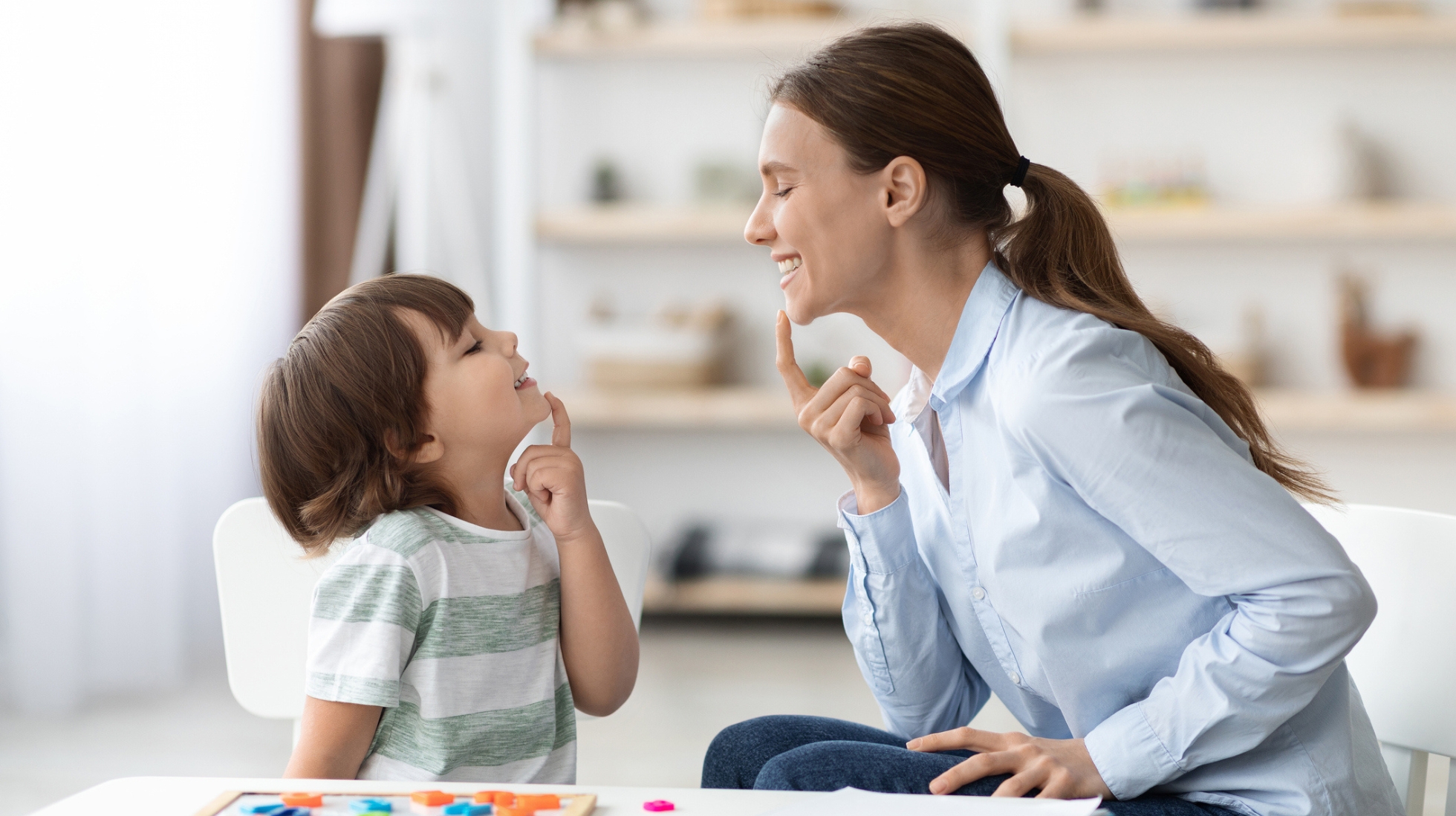 Lapsi ja nainen harjoittelevat viittomakieltä