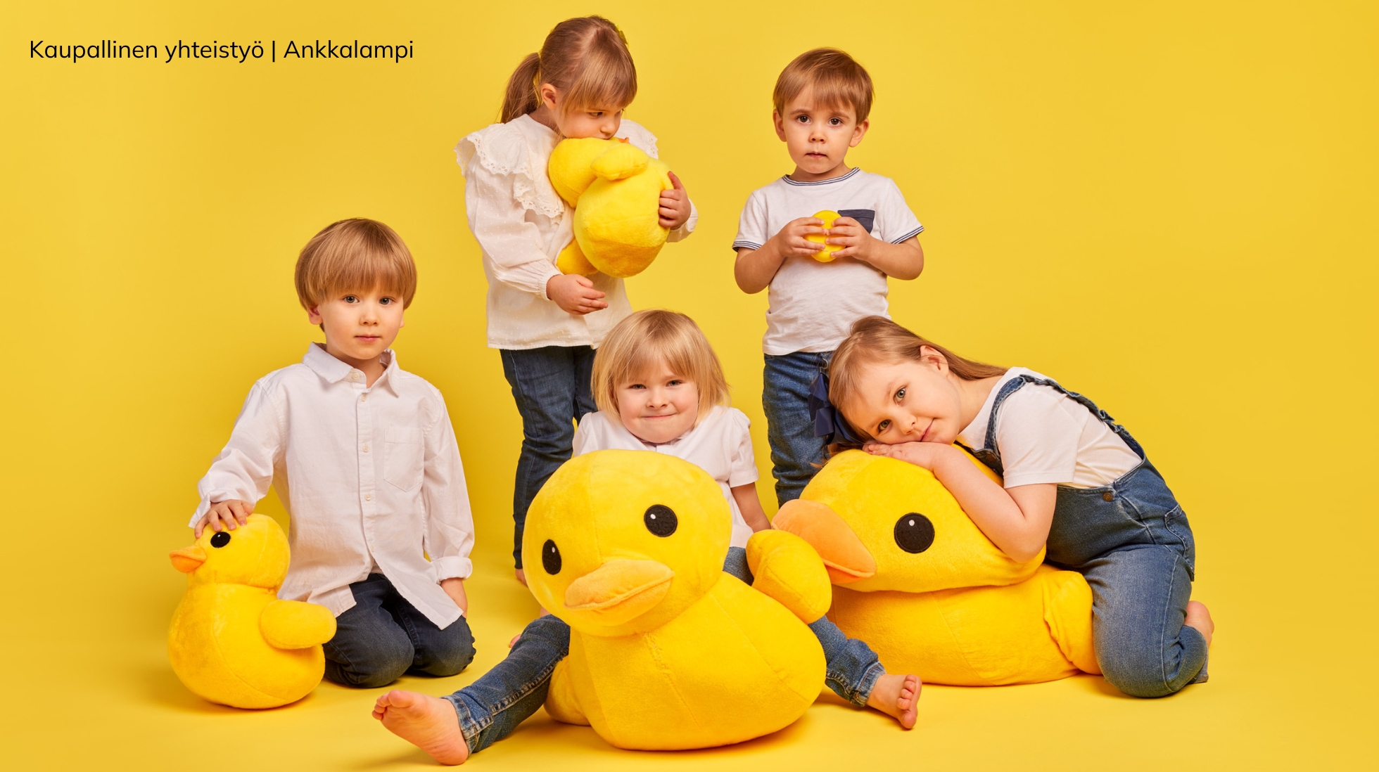 Keltaisen taustan edessä viisi lasta ja pehmoankkoja