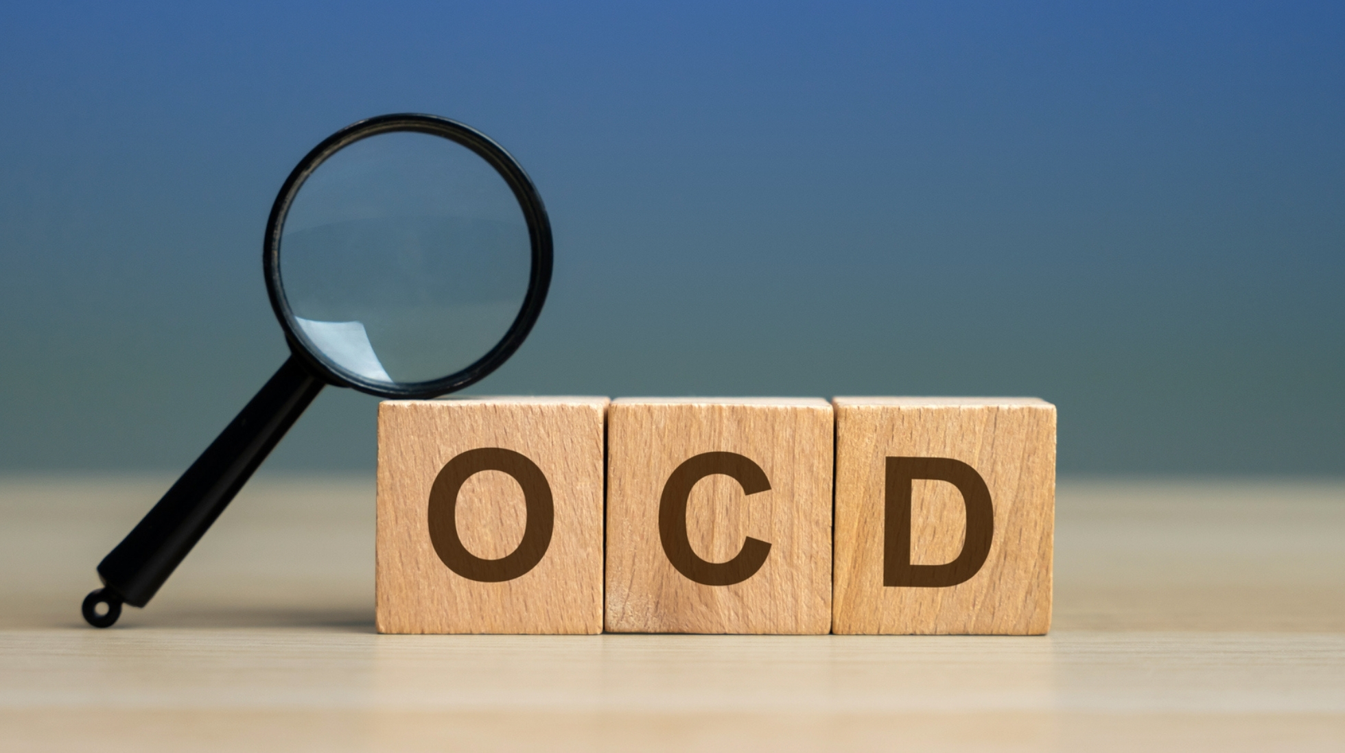 Suurennuslasi aseteltuna puisten kirjaimien päälle, jotka muodostavat sanan OCD