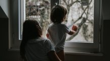 Helpot lasten leikit sisällä – näin taltutat tylsän sadepäivän Lapsi ja äiti katsovat ikkunasta. Ulkona sataa.